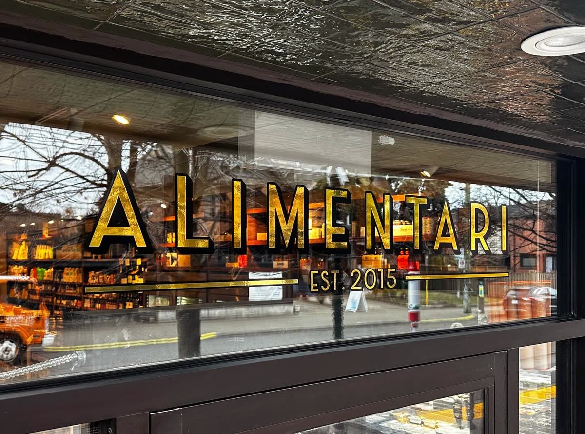 Window vinyl lettering on the glass storefront of Alimentari